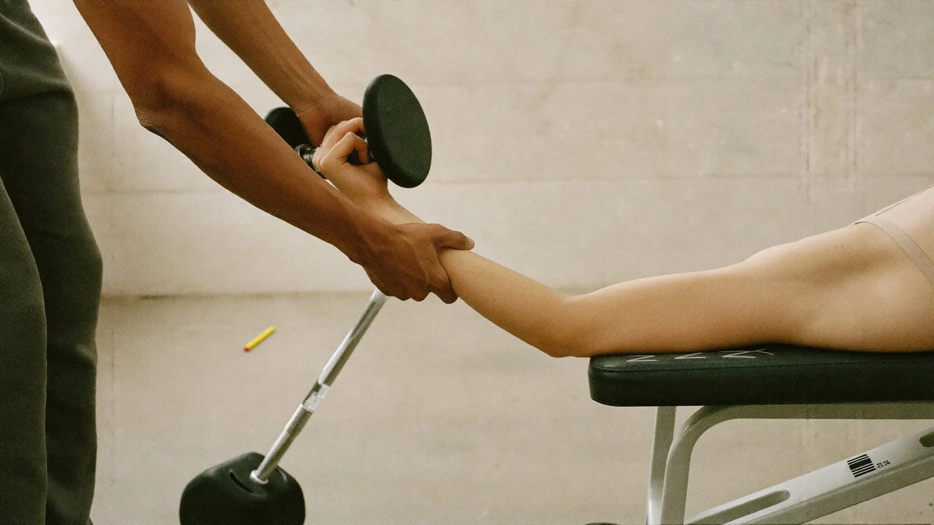 Entrenador guiando a un cliente durante un ejercicio con mancuernas en un gimnasio luminoso