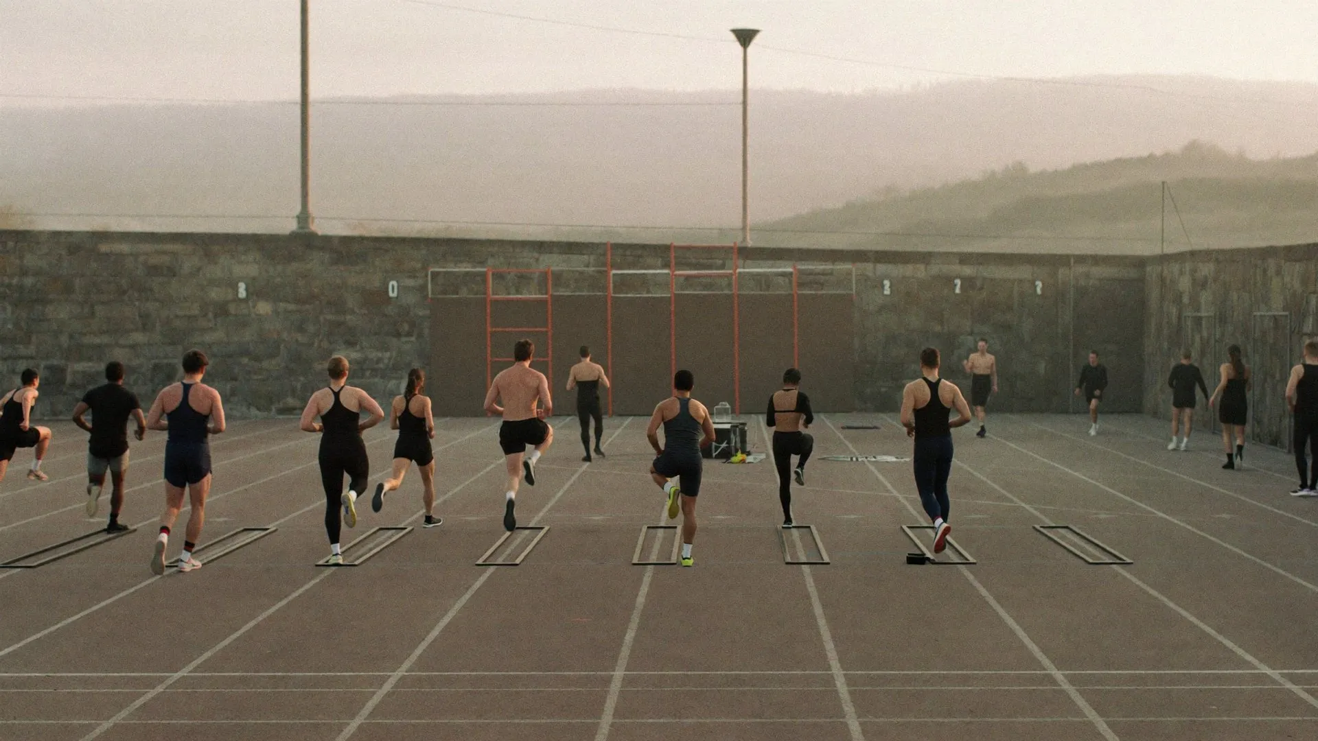 Grupo entrenando un circuito de resistencia en una pista de atletismo al amanecer